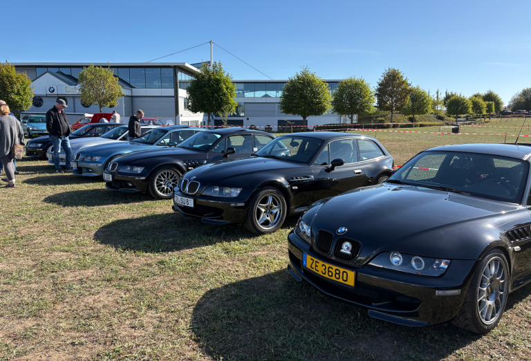 Drohnenaufnahme Mehrere Z3 Coupé parken entlang einer Straße, dazu stehen Personen zwischen den Fahrzeugen.